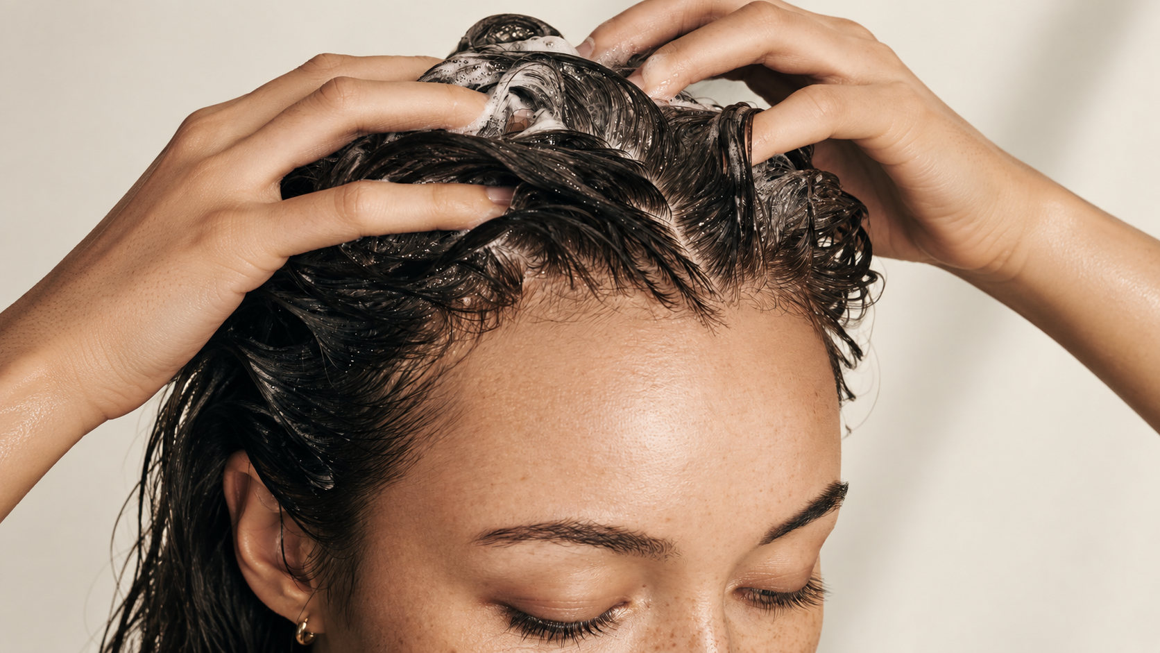 Close view of hair being washed at the scalp under running water